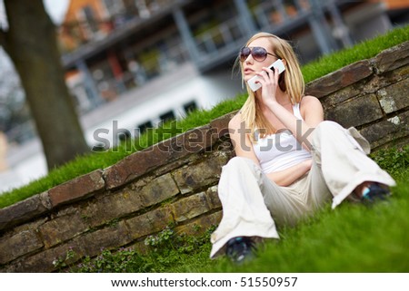 Young woman sitting with her cell phone in a park