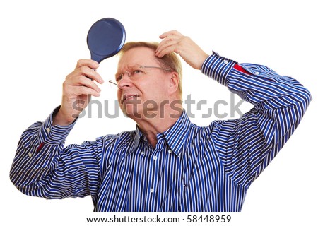 Eldery man watching his receding hair line in mirror