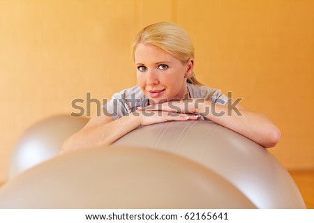 Happy woman in a gym with many gym balls