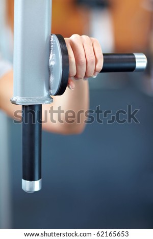 Female hand holding handle on training machine in gym