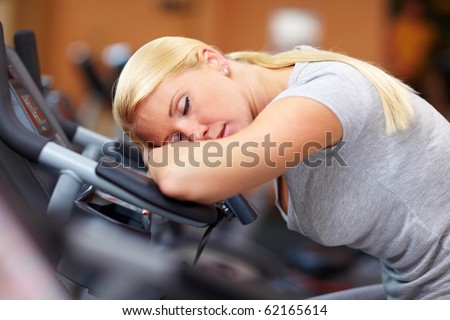 Sleeping woman in gym with her head on a hometrainer
