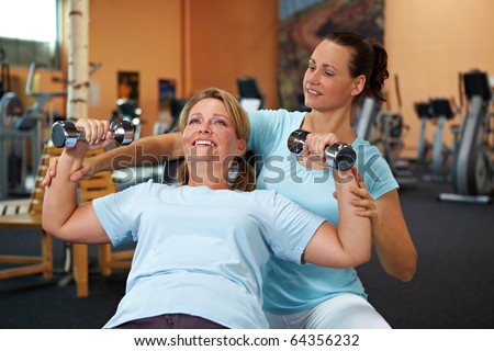 Woman doing weight training with female fitness coach