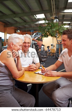 Fitness trainer in gym talking to new customers