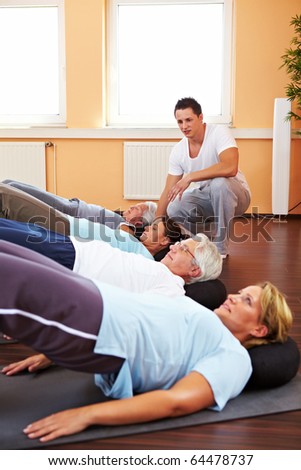 Group doing back exercises in a gym with fitness trainer