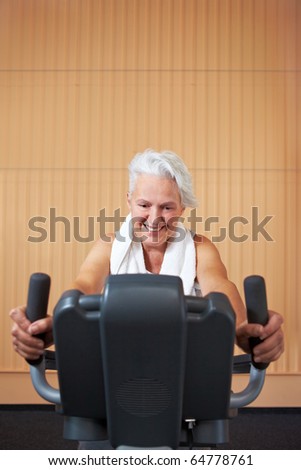 Elderly woman exercising on bicycle in a gym