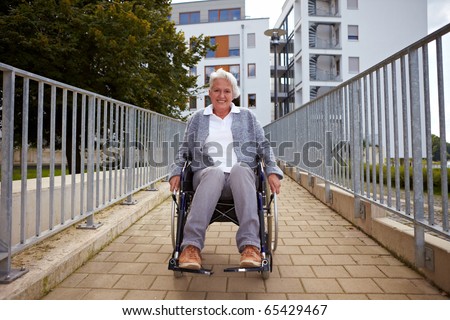 Happy elderly woman in wheelchair using a ramp