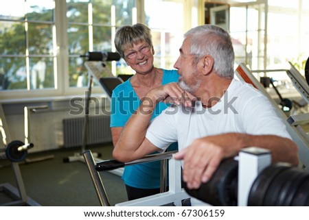 Two happy senior people talking in gym