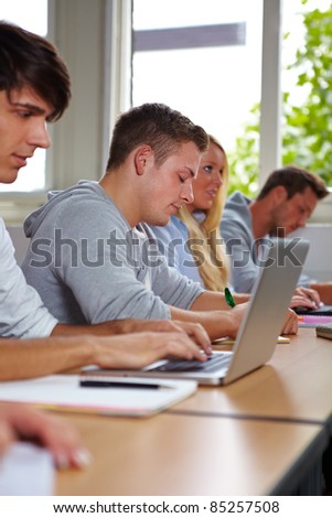 Student taking notes at laptop in university class