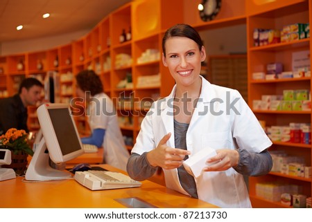 Happy pharmacist in pharmacy pointing to medical product