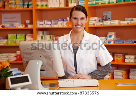 Happy pharmacist standing at checkout counter in a drugstore