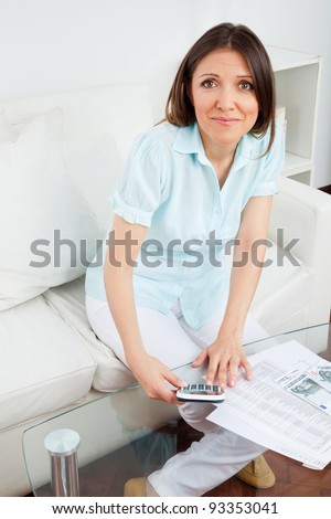 Woman with money and calculator in her living room