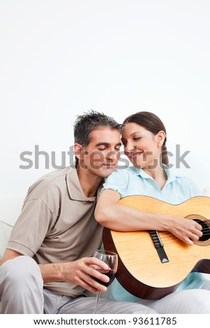 Man with wine and woman with guitar in living room