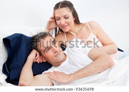 Unhappy man in bed turning away from seducing woman