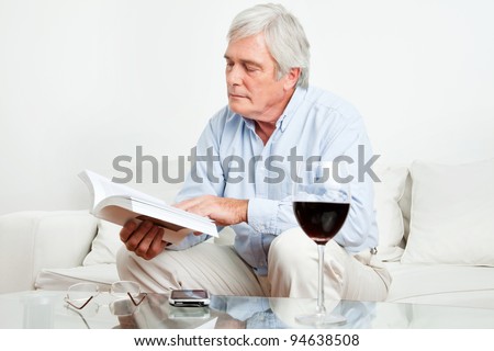 Senior man reading a book on the couch in the living room