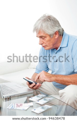 Senior man at home with calculator, laptop and Euro money