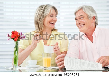 Happy smiling senior couple eating breakfast at home