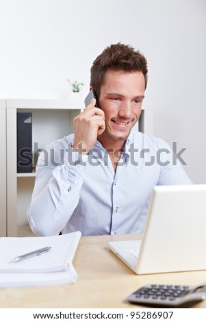 Happy university student making cell phone call at desk