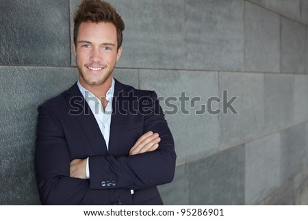 Young urban business man leaning on wall