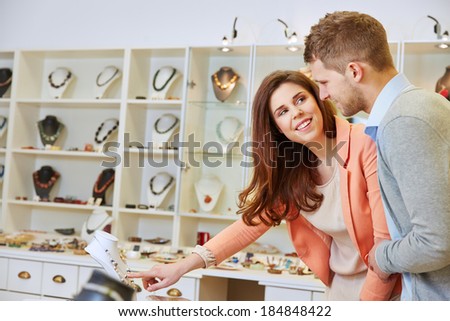Happy woman with man pointing to necklace in a jewelry store