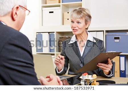 Elderly female consultant in bank talking to senior customer