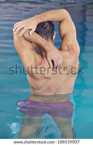Man with muscles doing back training in aqua fitness swimming pool