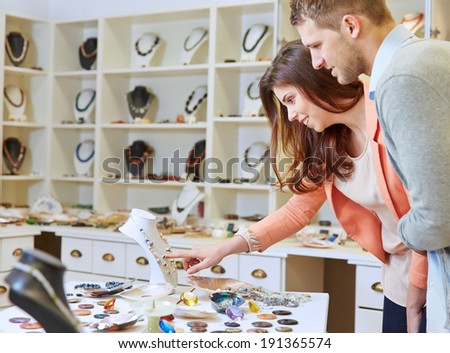 Smiling couple shopping in jewelry store for a necklace