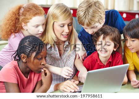 Students and teacher using internet on computer for research in elementary school class