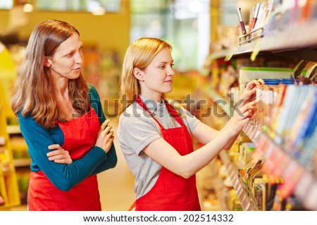 Internship organizing shelves in supermarket under supervision of the store manager