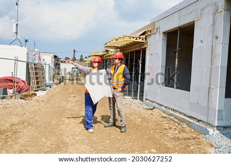 Architect with construction drawing gives foreman instructions on a building site in the shell Photo stock © 
