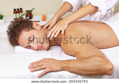 Relaxed man getting thai massage for his back in a day spa