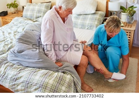 Elderly care worker helps senior citizen put on slippers at home or in a retirement home Foto stock © 