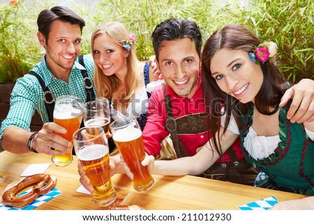 Friends in bavaria clinking beer glasses in summer in a beer garden