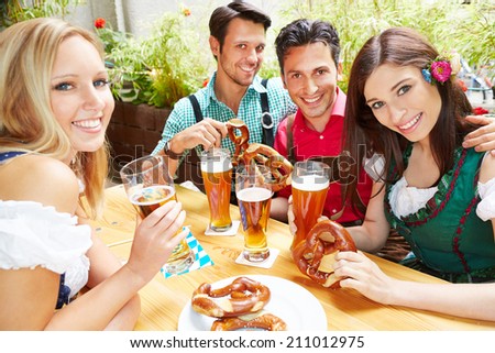 Happy group of people drinking beer together in garden in summer