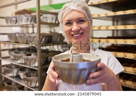 Young woman as a proud apprentice baker with a freshly baked Gugelhupf cake 商業照片 © 