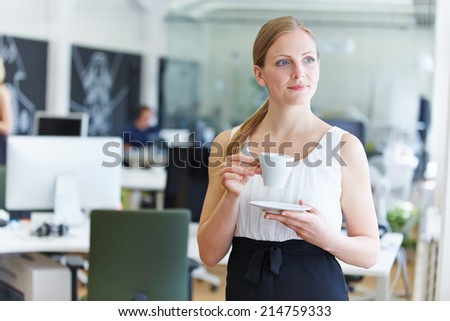 Woman in office drinking coffee during her break