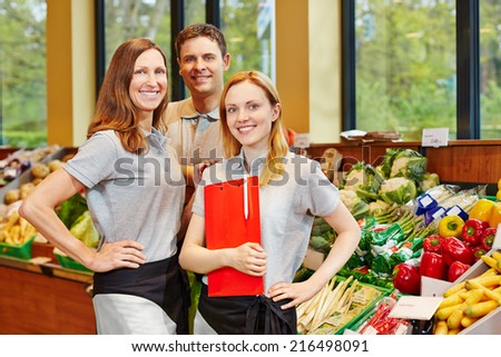 Team of smiling store manager and happy salespeople in a supermarket
