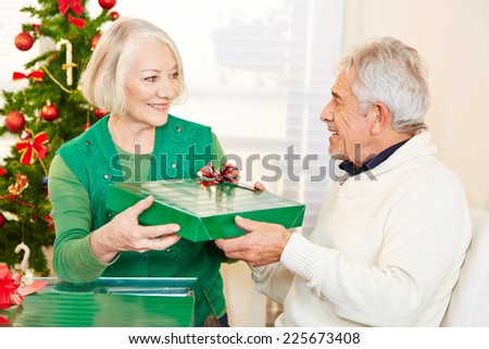 Two happy senior citizens celebrating christmas with gifts