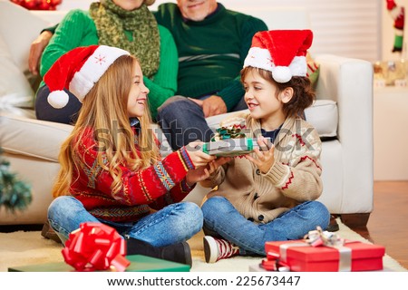 Siblings giving gifts to each other at christmas at their grandparents