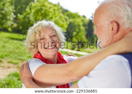 Two happy seniors in love dancing together in nature in summer