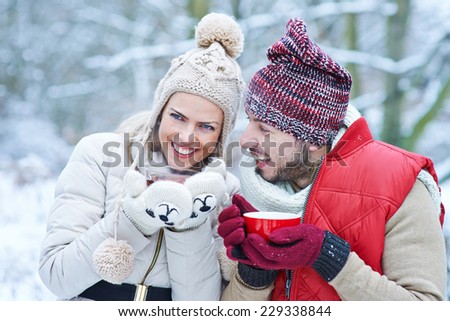 Happy couple laughing together with hot tea in winter
