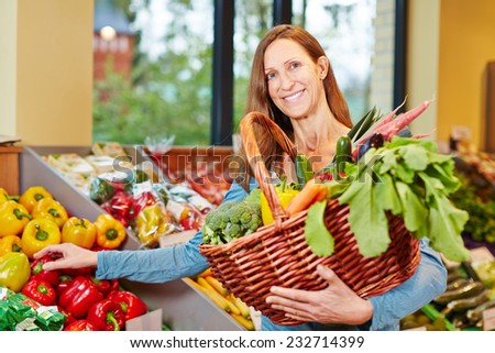 Attractive elderly woman buying fresh vegetables in organic food store