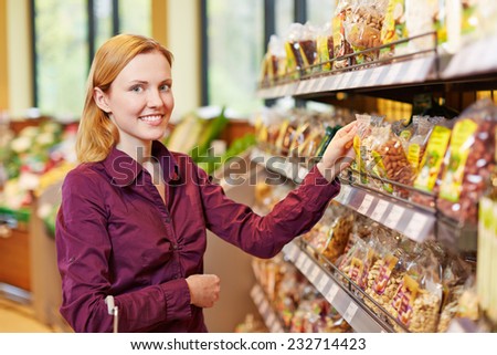 Young smiling woman buying a bag of nuts in a supermarket