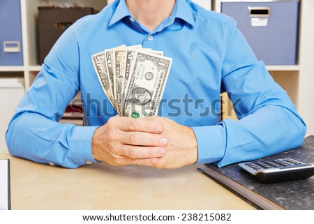 Hands holding many dollar bills as fan on the desk