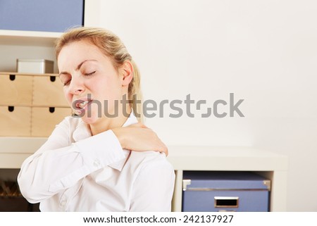 Business woman standing in office with pain in her shoulder