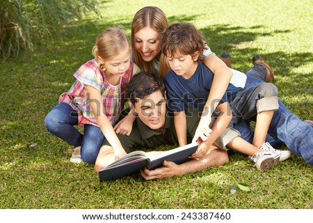 Happy family with children reading a book together in a garden