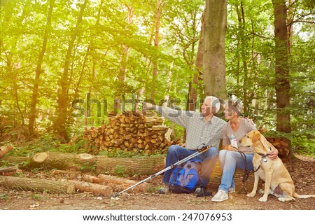 Senior couple with dog seeing goal of hiking trip in a forest