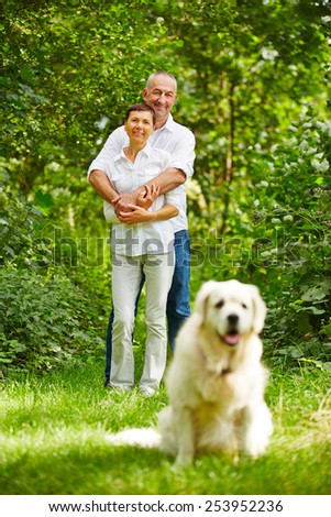 Senior couple with golden retriever dog as a pet in their garden