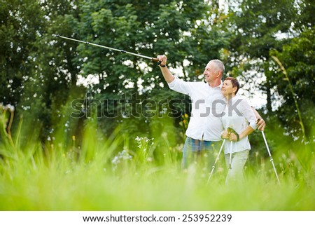 Senior couple hiking and man pointing to the distance with walking stick