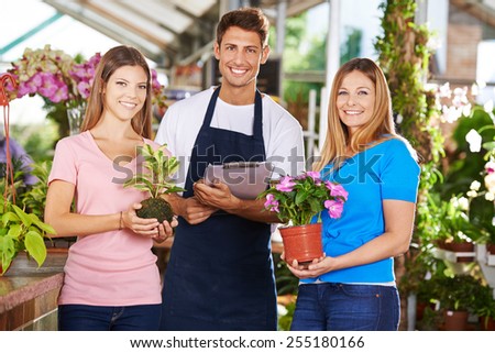 Happy gardener team group in nursery shop with plants and flowers
