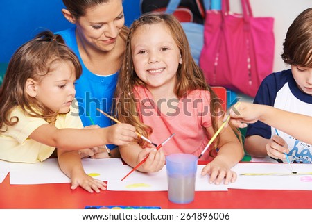Art teacher and children painting images together in elementary school